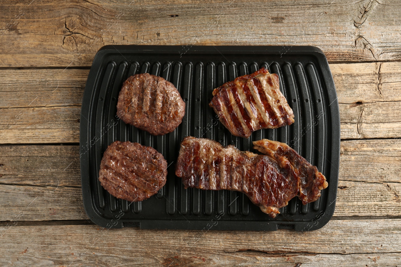 Photo of Delicious grilled beef meat on wooden table, top view