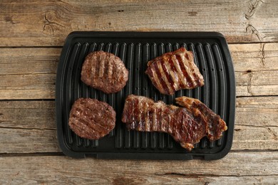 Photo of Delicious grilled beef meat on wooden table, top view