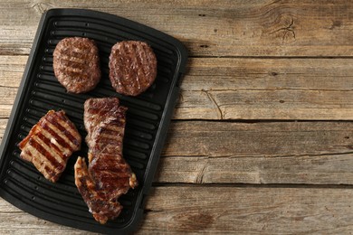 Photo of Delicious grilled beef meat on wooden table, top view. Space for text