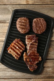 Photo of Delicious grilled beef meat on wooden table, top view