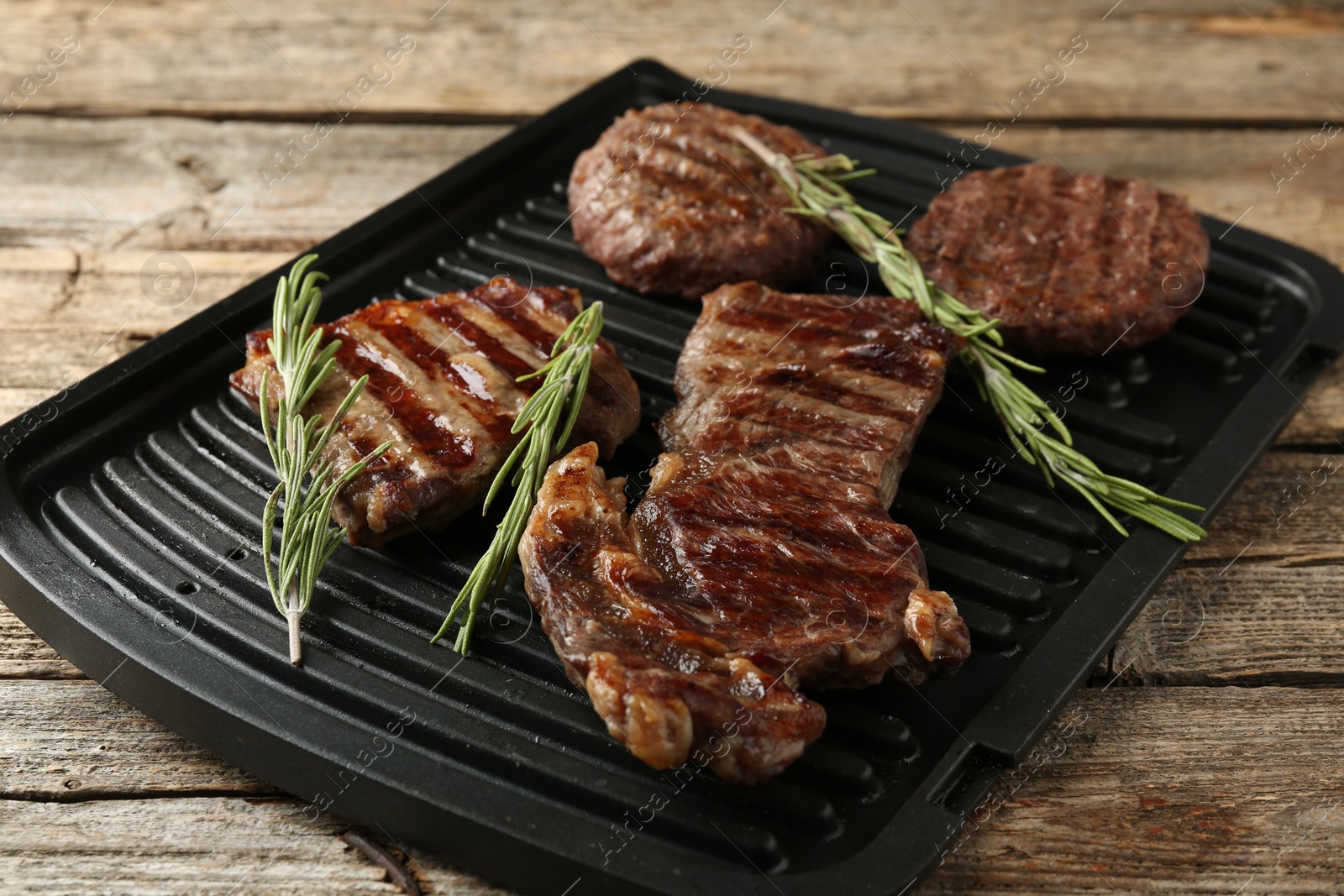 Photo of Delicious grilled beef meat with rosemary on wooden table, closeup