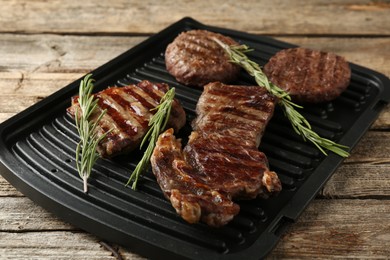 Photo of Delicious grilled beef meat with rosemary on wooden table, closeup