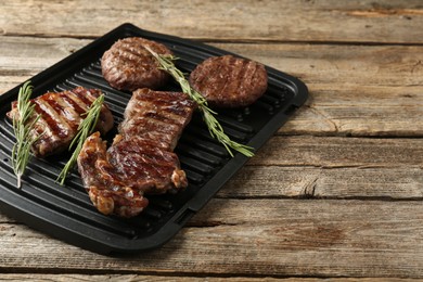 Photo of Delicious grilled beef meat with rosemary on wooden table, closeup. Space for text