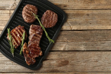 Photo of Delicious grilled beef meat with rosemary on wooden table, top view. Space for text