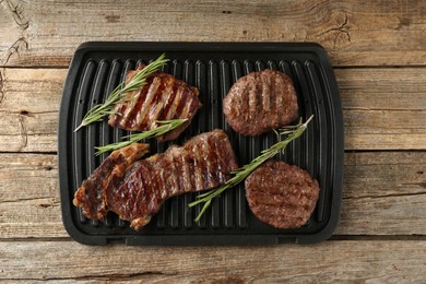 Photo of Delicious grilled beef meat with rosemary on wooden table, top view