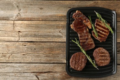 Photo of Delicious grilled beef meat with rosemary on wooden table, top view. Space for text