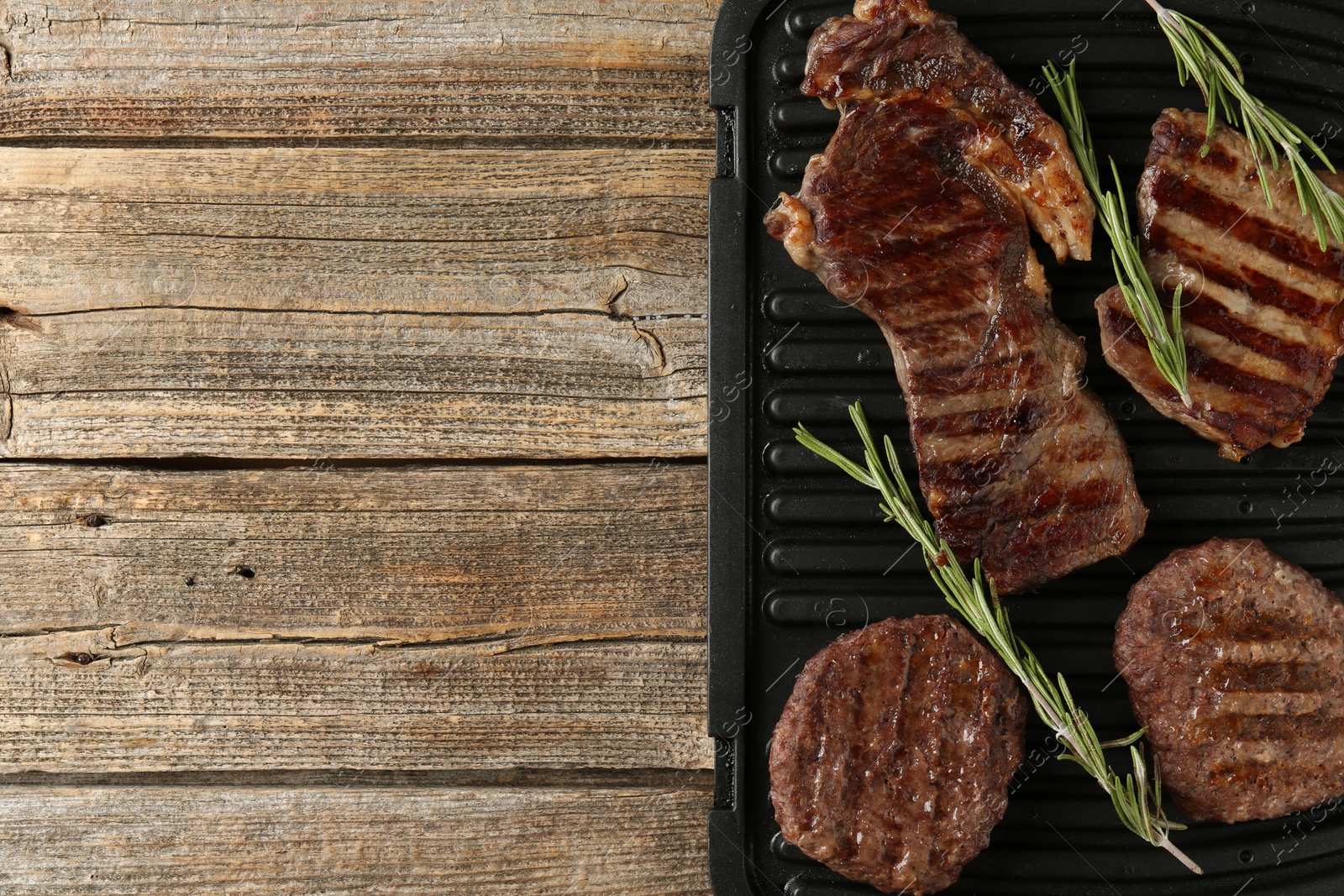 Photo of Delicious grilled beef meat with rosemary on wooden table, top view. Space for text