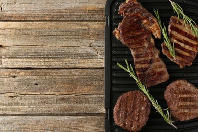 Photo of Delicious grilled beef meat with rosemary on wooden table, top view. Space for text