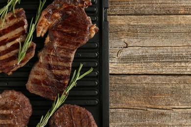 Photo of Delicious grilled beef meat with rosemary on wooden table, top view. Space for text