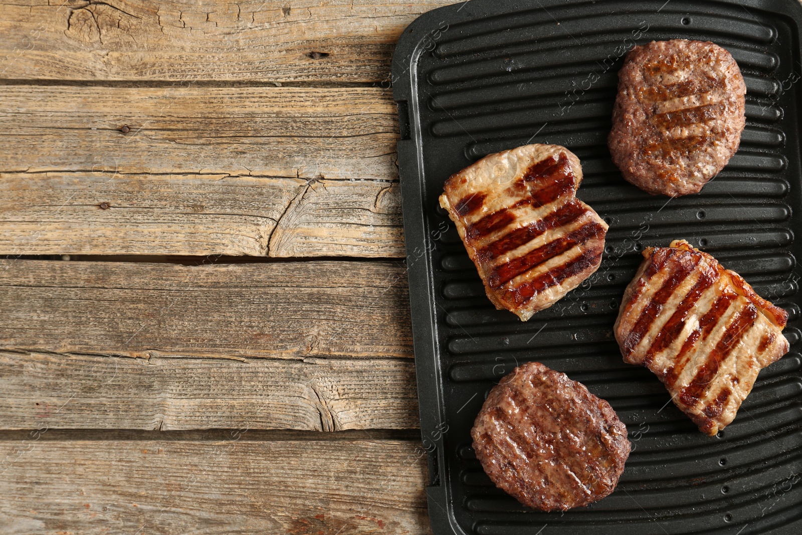 Photo of Delicious grilled beef meat on wooden table, top view. Space for text