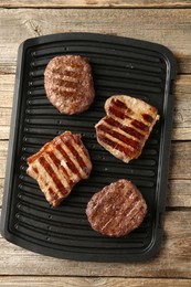 Photo of Delicious grilled beef meat on wooden table, top view