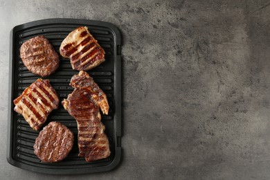 Photo of Delicious grilled beef meat on grey table, top view. Space for text