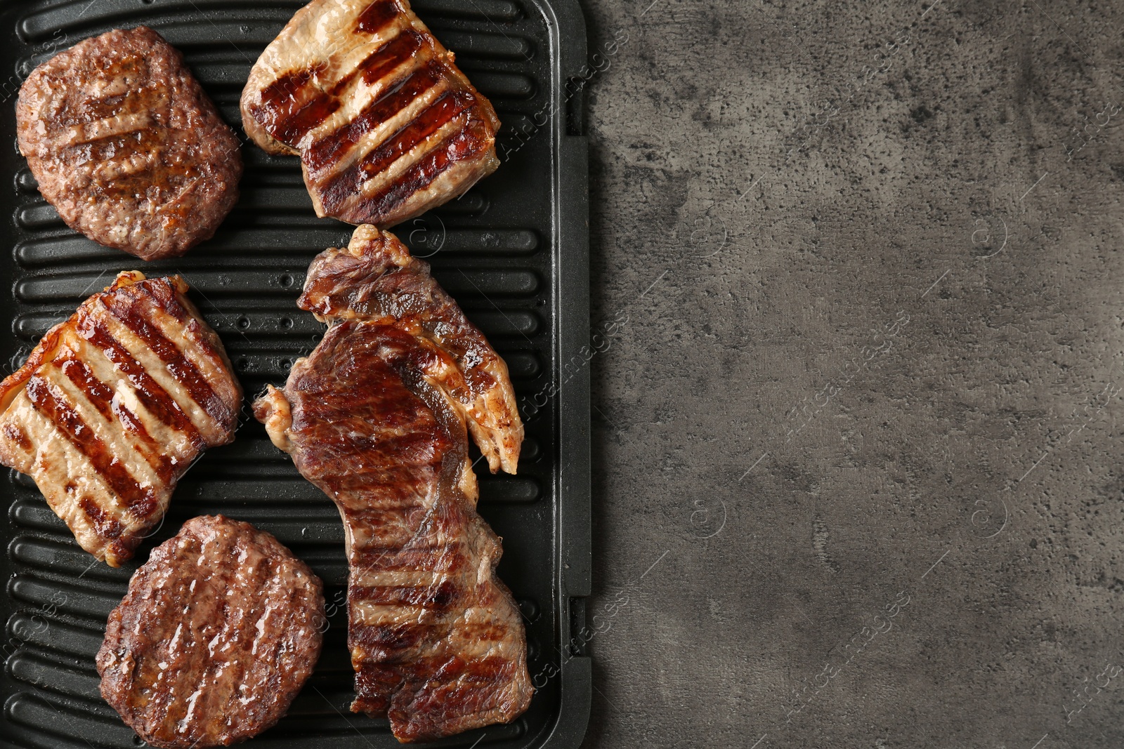 Photo of Delicious grilled beef meat on grey table, top view. Space for text