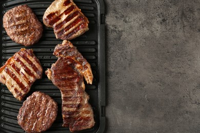 Photo of Delicious grilled beef meat on grey table, top view. Space for text