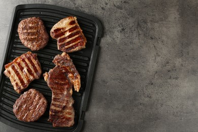 Photo of Delicious grilled beef meat on grey table, top view. Space for text