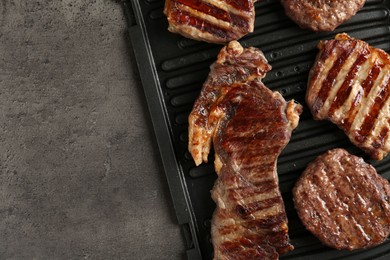 Photo of Delicious grilled beef meat on grey table, top view. Space for text