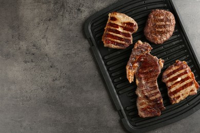 Photo of Delicious grilled beef meat on grey table, top view. Space for text