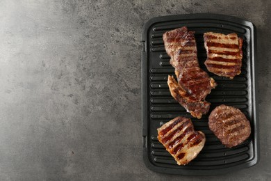 Photo of Delicious grilled beef meat on grey table, top view. Space for text