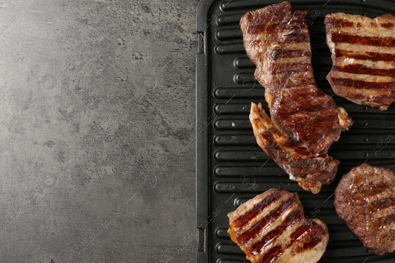 Photo of Delicious grilled beef meat on grey table, top view. Space for text