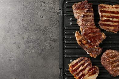 Photo of Delicious grilled beef meat on grey table, top view. Space for text