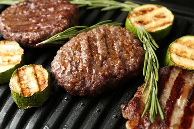 Photo of Electric grill with beef steaks, zucchini and rosemary, closeup