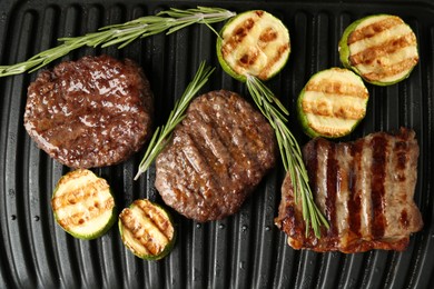 Photo of Electric grill with beef steaks, zucchini and rosemary, closeup