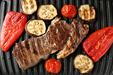 Photo of Electric grill with beef steaks and vegetables, closeup