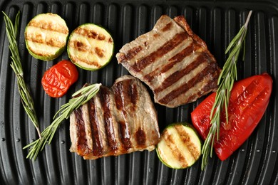 Photo of Electric grill with beef steaks, vegetables and rosemary, closeup