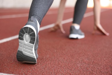 Photo of Woman in starting position for run at stadium, closeup