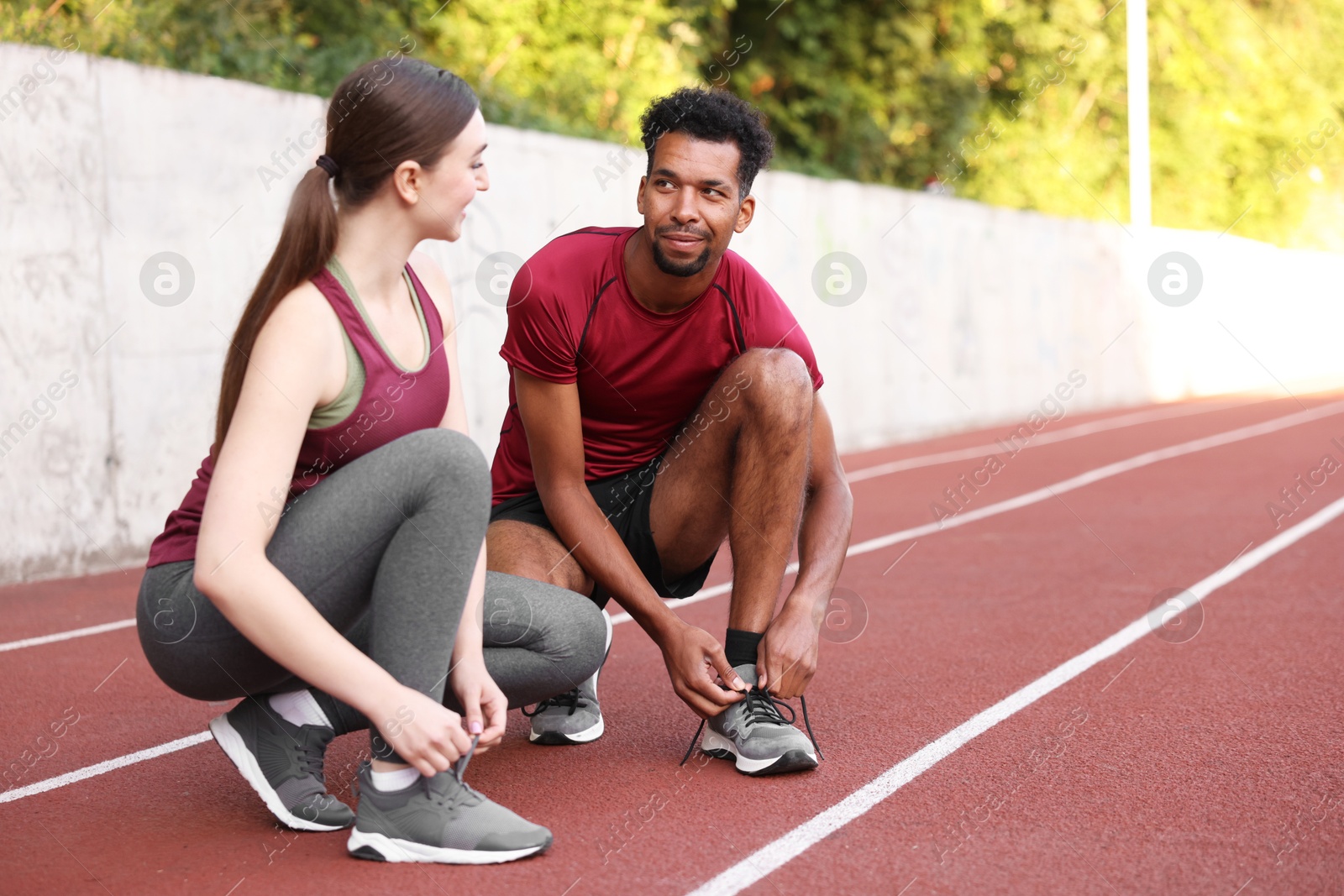 Photo of Runners tying shoelaces of their sneakers at stadium. Space for text