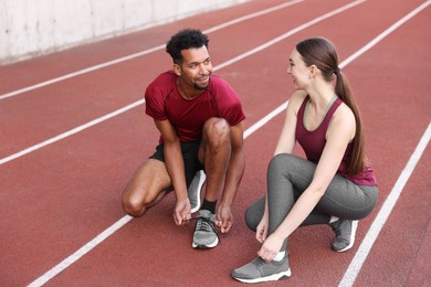 Photo of Runners tying shoelaces of their sneakers at stadium