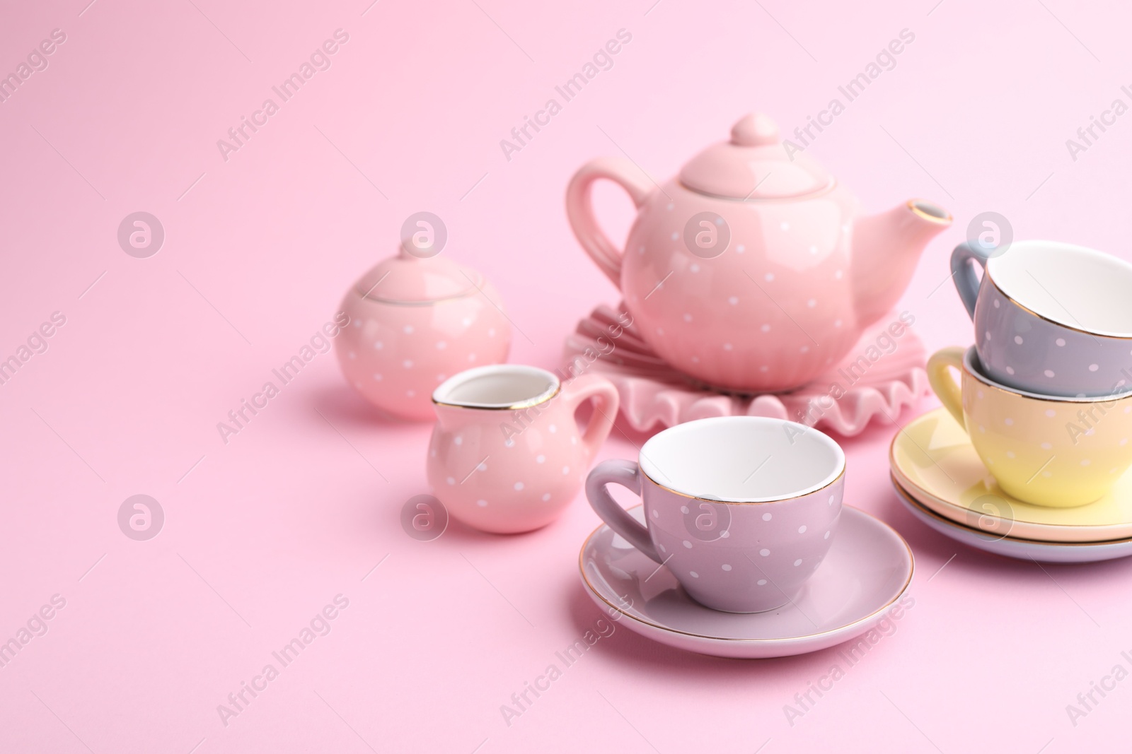 Photo of Beautiful tea set on pink background, space for text. Child's toy