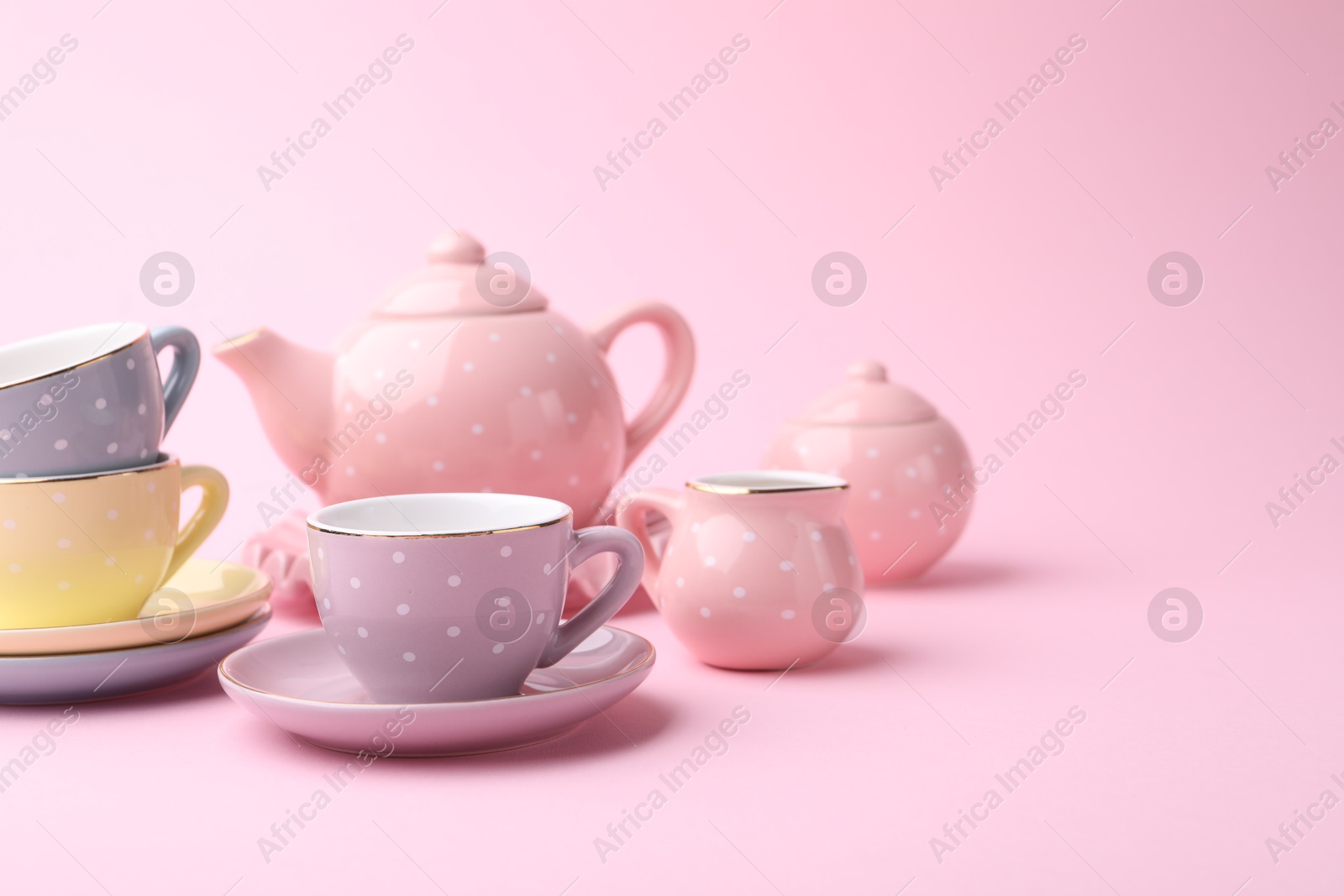 Photo of Beautiful tea set on pink background, space for text. Child's toy
