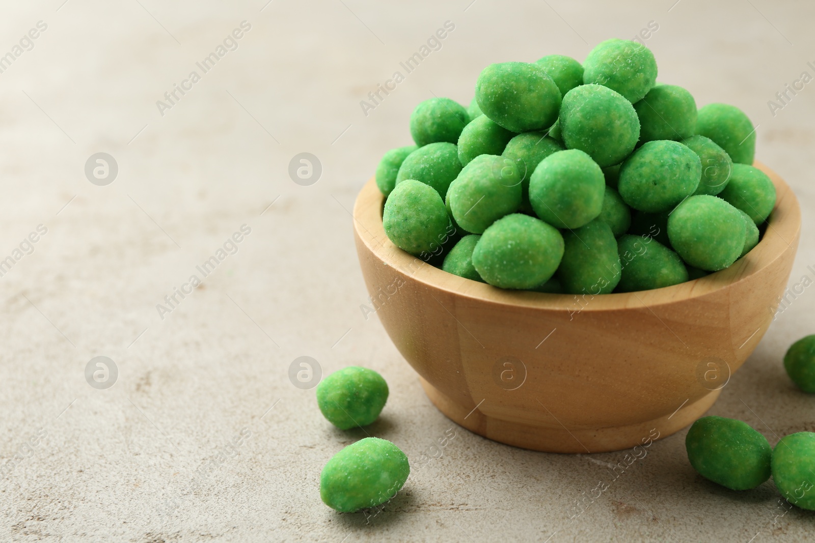 Photo of Wasabi coated peanuts in bowl on light table, closeup. Space for text