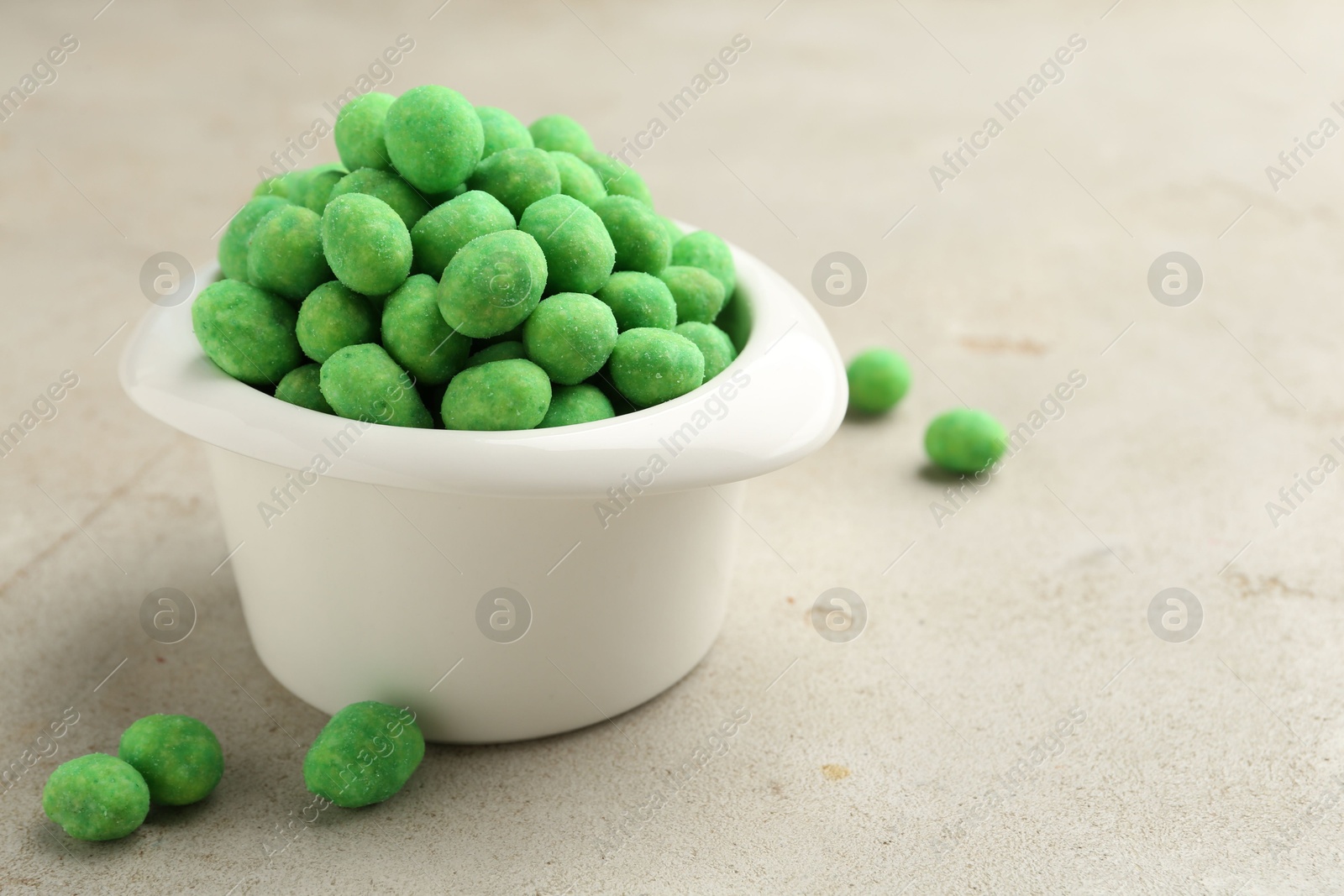 Photo of Wasabi coated peanuts in bowl on light table, closeup. Space for text