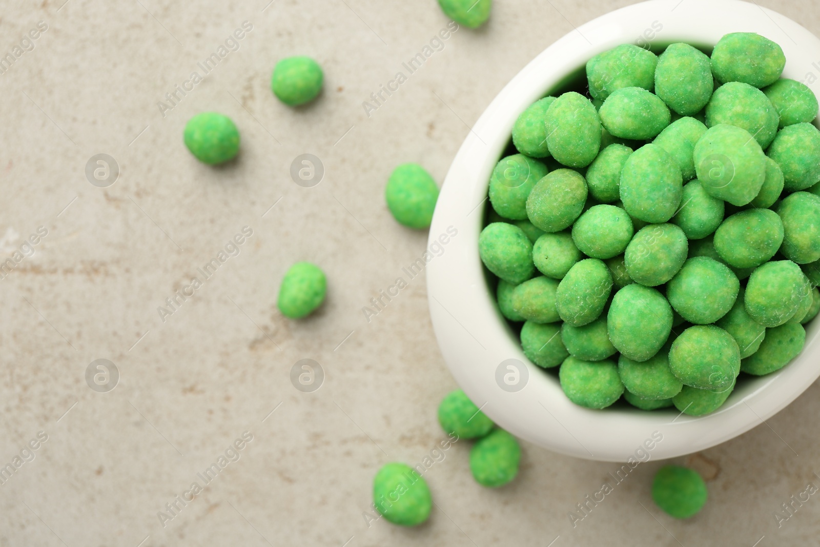 Photo of Wasabi coated peanuts in bowl on light table, top view
