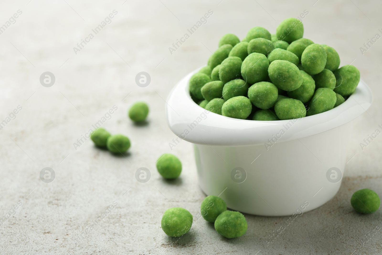 Photo of Wasabi coated peanuts in bowl on light table, closeup. Space for text