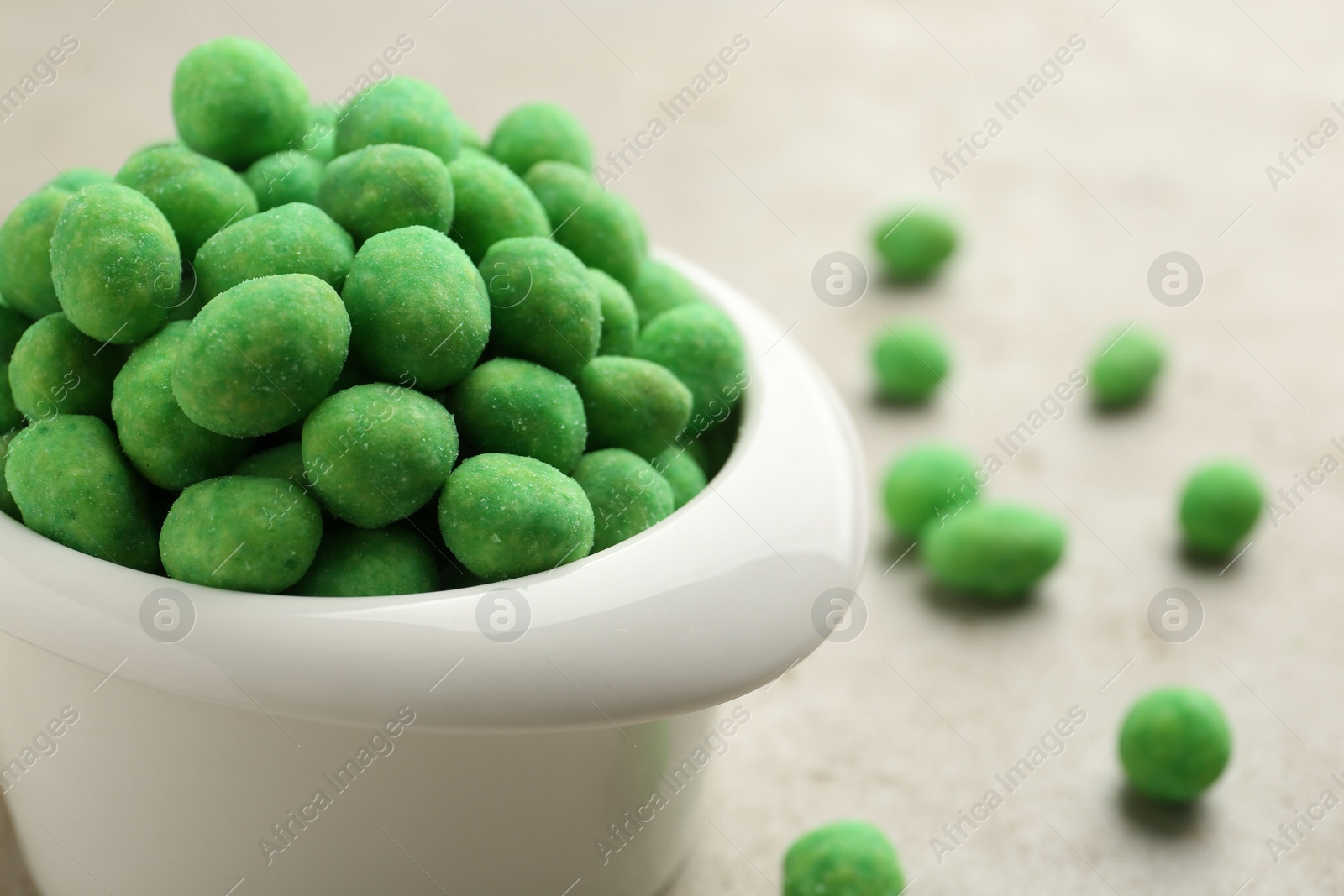 Photo of Wasabi coated peanuts in bowl on light table, closeup