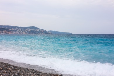 Photo of Beautiful view of wavy sea, city and pebbles on beach