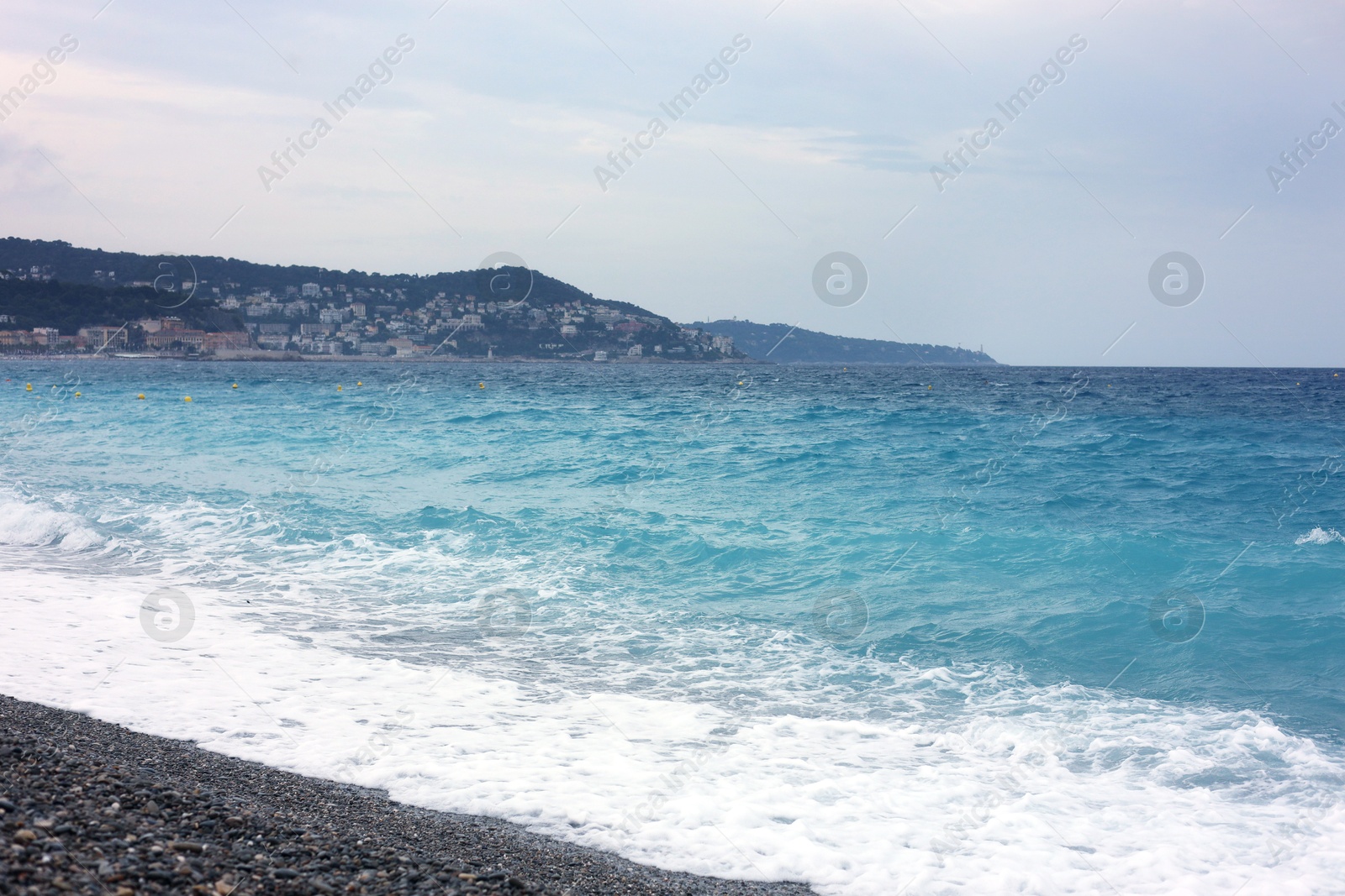 Photo of Beautiful view of wavy sea, city and pebbles on beach