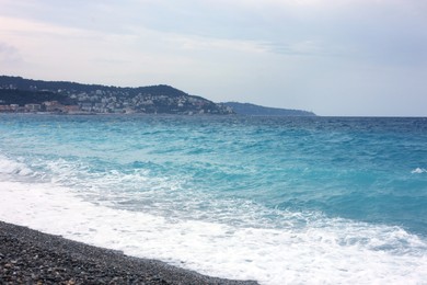 Photo of Beautiful view of wavy sea, city and pebbles on beach