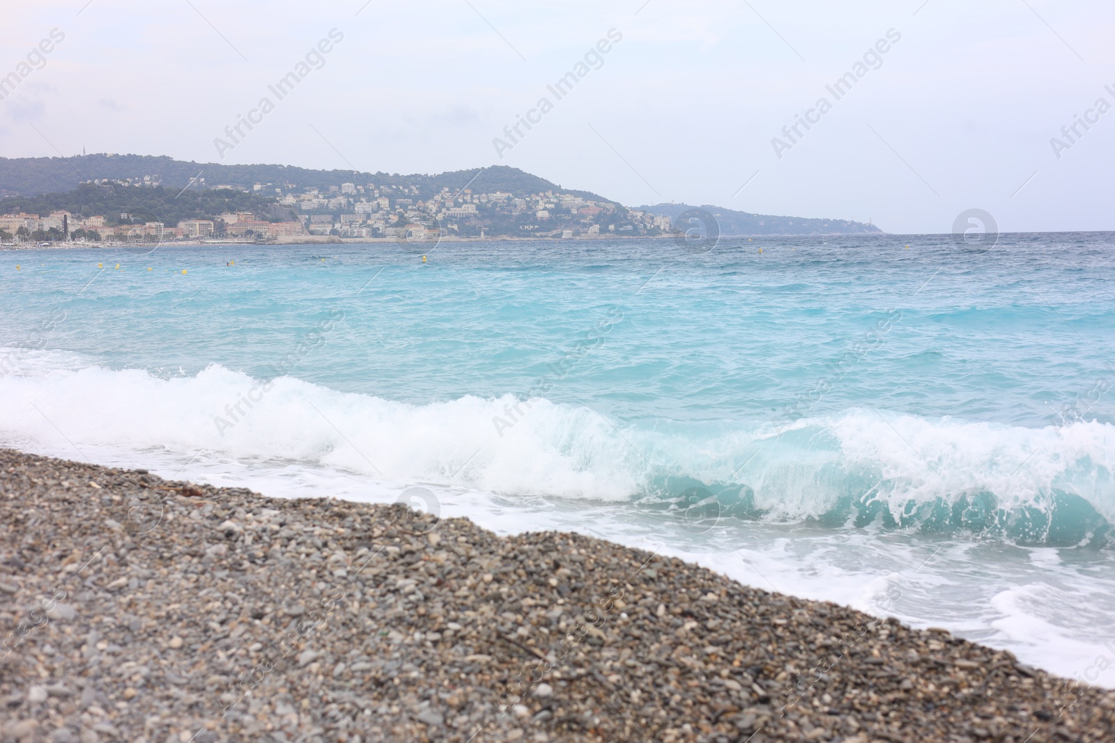 Photo of Beautiful view of wavy sea, city and pebbles on beach