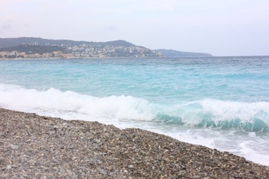 Photo of Beautiful view of wavy sea, city and pebbles on beach