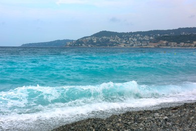 Photo of Beautiful view of wavy sea, city and pebbles on beach