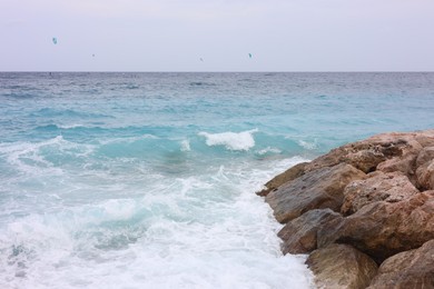 Photo of Beautiful view of wavy sea, rocks and pebbles on beach