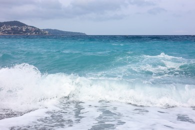 Photo of Beautiful view of wavy sea, city and pebbles on beach