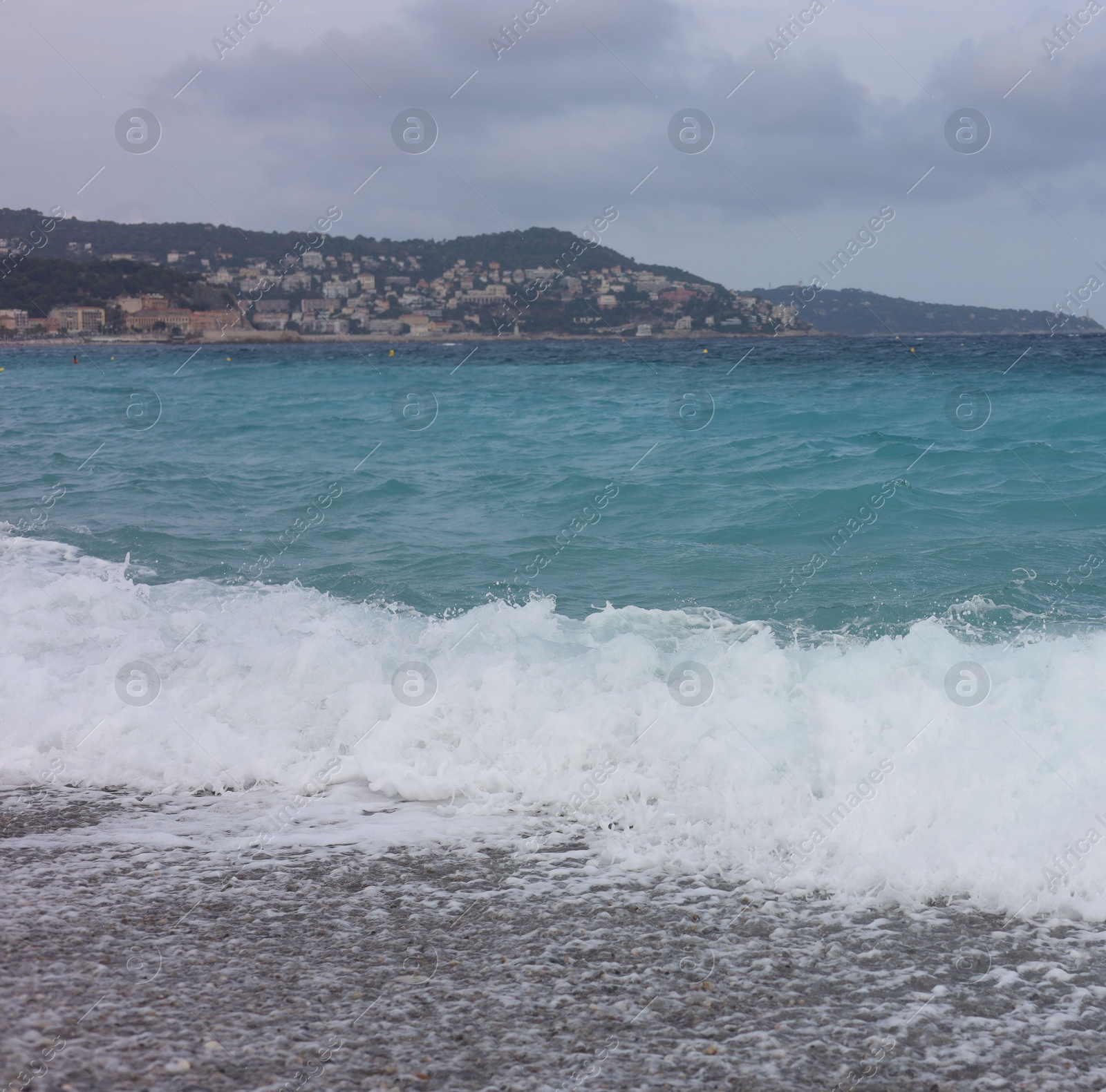 Photo of Beautiful view of wavy sea, city and pebbles on beach