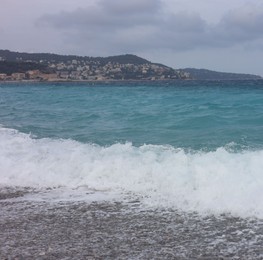 Photo of Beautiful view of wavy sea, city and pebbles on beach
