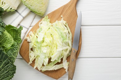 Photo of Fresh cut Savoy cabbage and knife on white table, flat lay. Space for text