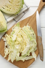 Photo of Fresh cut Savoy cabbage and knife on white table, flat lay